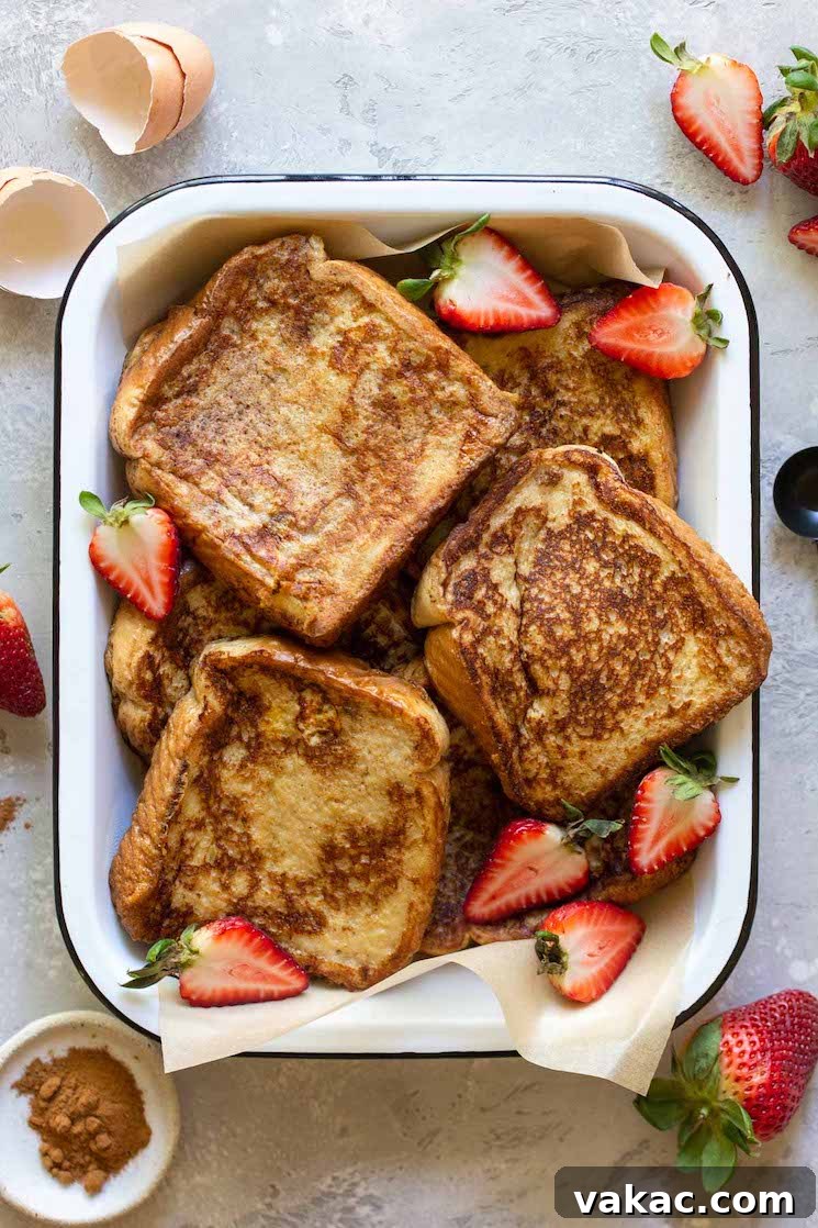 Unforgettable French Toast 2 A baking pan filled with finished French toast surrounded by strawberries and spices, ready to be served for breakfast or brunch.
