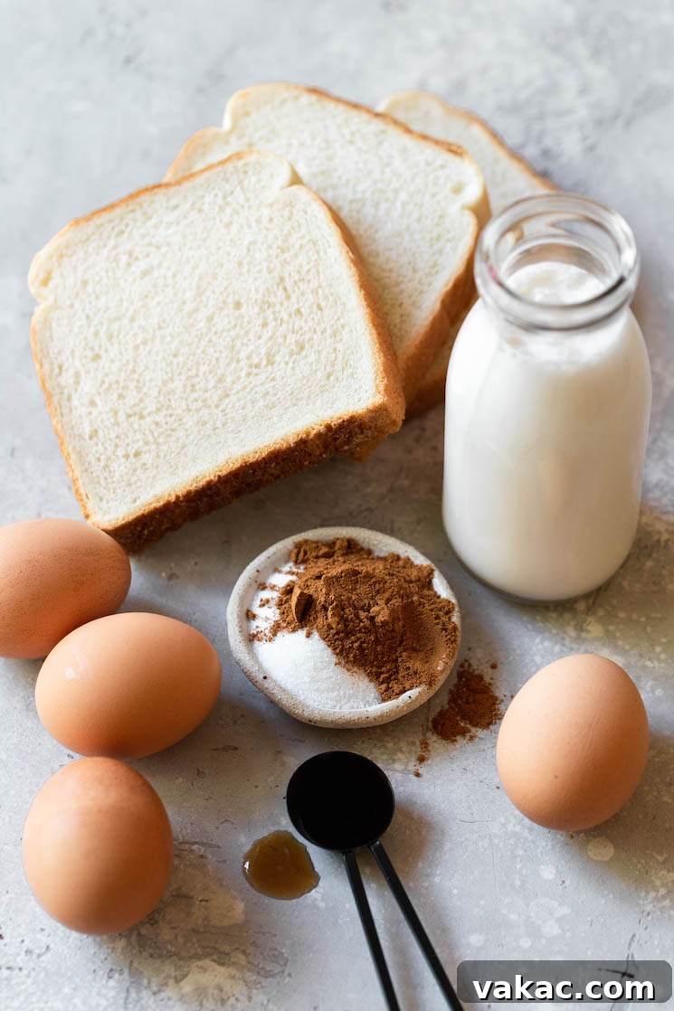 Unforgettable French Toast 3 Essential ingredients for making French toast, including eggs, milk, cream, sugar, vanilla, and cinnamon, neatly arranged on a rustic gray surface.