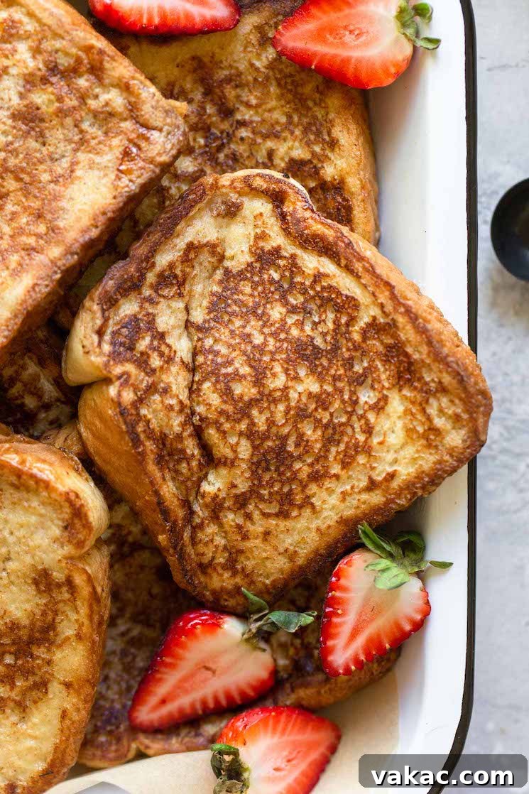 Unforgettable French Toast 6 A close up image of perfectly cooked French toast in a baking pan, generously topped with fresh halved strawberries, highlighting its delicious texture.