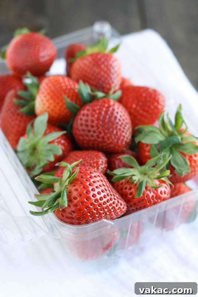 Blushing Berry Zest 3 Close-up of fresh, ripe strawberries and whole green limes on a wooden surface, ready for making limeade