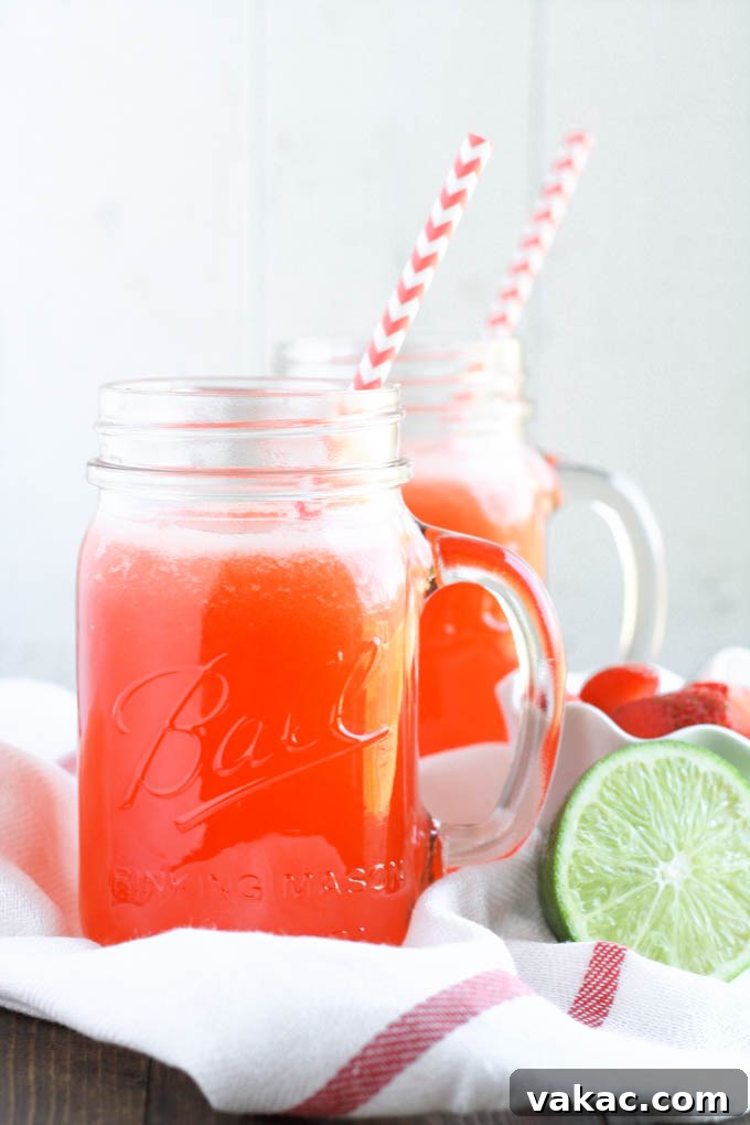 Blushing Berry Zest 4 Strawberry Limeade in a elegant glass pitcher with sliced fruit and a full glass, ready for a summer party