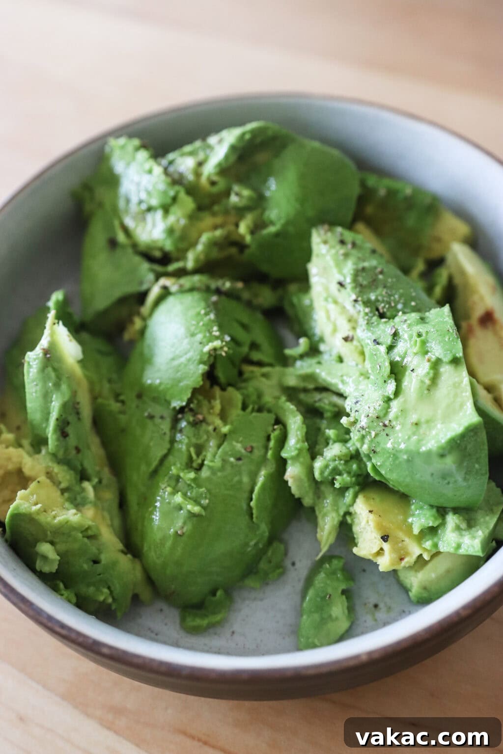 Speedy Creamy Greek Yogurt Guacamole 5 Ripe avocados being scooped into a white bowl with lime and lemon juice, ready for mashing