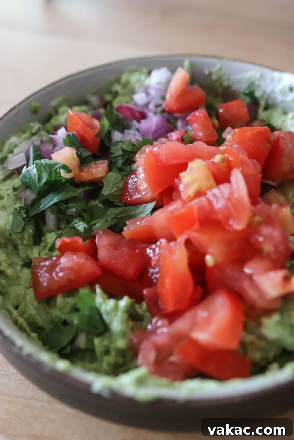Speedy Creamy Greek Yogurt Guacamole 7 Plain Greek yogurt, diced tomato, red onion, and chopped cilantro being gently folded into mashed avocado