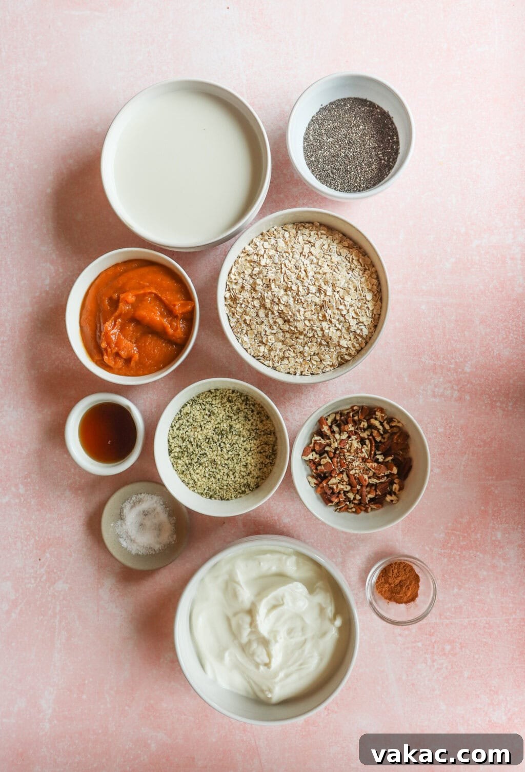 Effortless Autumn Bliss: Pumpkin Pie Spice Overnight Oats 3 Ingredients for Easy & Filling Pumpkin Pie Spice Overnight Oats in a small white bowls, including rolled oats, milk, pumpkin puree, Greek yogurt, maple syrup, chia seeds, hemp hearts, pumpkin pie spice, salt, pecans