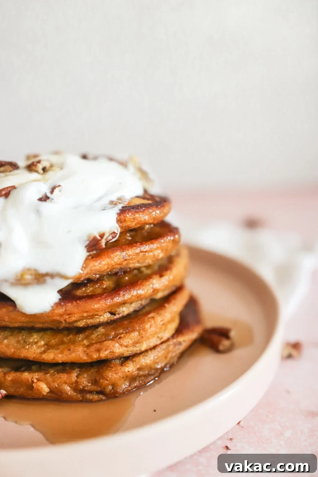 Power-Packed Pumpkin Cottage Cheese Pancakes 2 A stack of High Protein Pumpkin Pancakes with Cottage Cheese on a pink plate with a dollop of Greek yogurt, drizzled with maple syrup