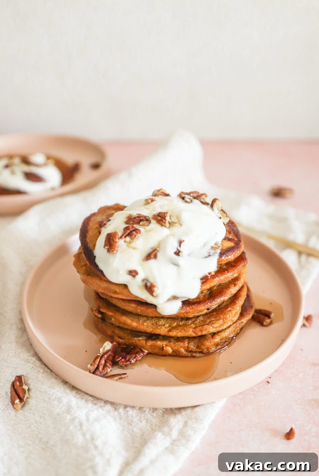 Power-Packed Pumpkin Cottage Cheese Pancakes 8 A stack of High Protein Pumpkin Pancakes with Cottage Cheese on a pink plate with a dollop of Greek yogurt, berries, and pecans