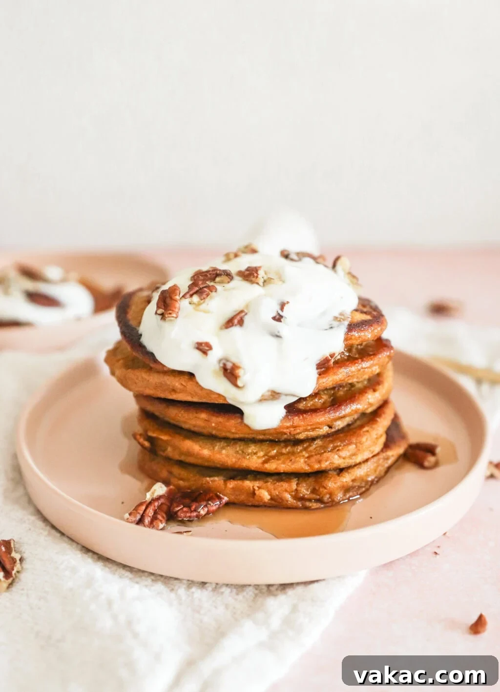 Power-Packed Pumpkin Cottage Cheese Pancakes 9 A stack of High Protein Pumpkin Pancakes with Cottage Cheese on a pink plate with a dollop of Greek yogurt and a drizzle of maple syrup, garnished with a sprig of mint