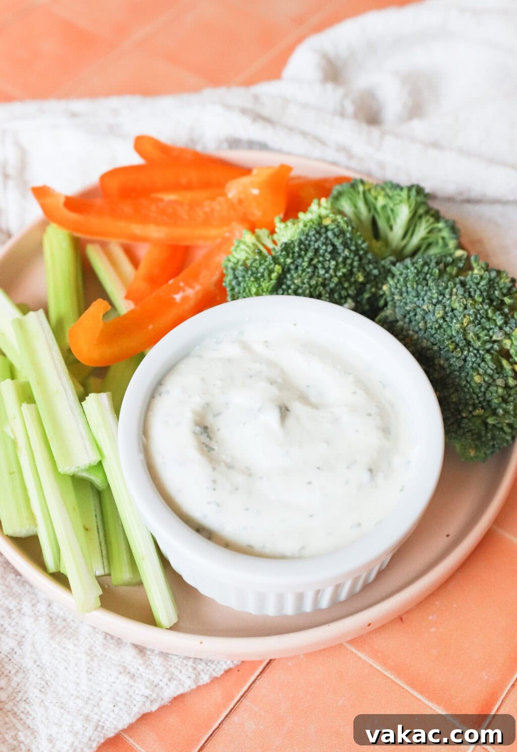 Quick 3-Ingredient Protein Packed Cottage Cheese Ranch Dip 6 final image of the high protein cottage cheese ranch dip, with celery, peppers and broccoli on a light pink plate, on an orange countertop