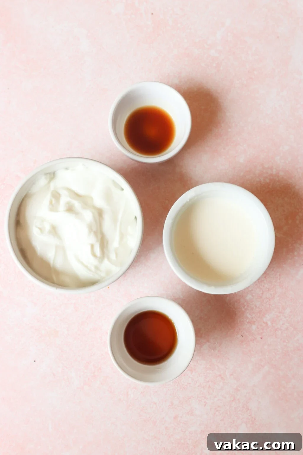 Greek Yogurt Whip: The Speedy, Guilt-Free Dessert Topping 3 Four small bowls on a pink surface containing key ingredients for making Greek yogurt whipped cream: yogurt, cream, vanilla extract, and sweetener.