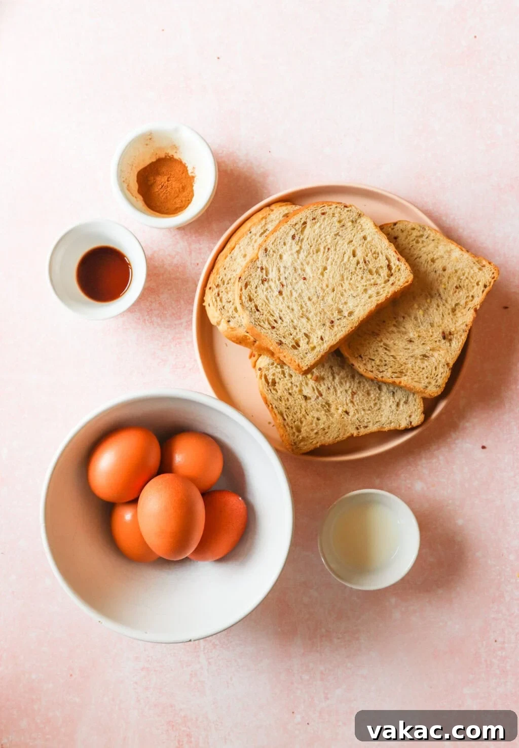 Pillowy Cinnamon-Kissed Sheet Pan French Toast Bake 3 All the ingredients for sheet pan French toast laid out in bowls on a pink countertop, ready for preparation.