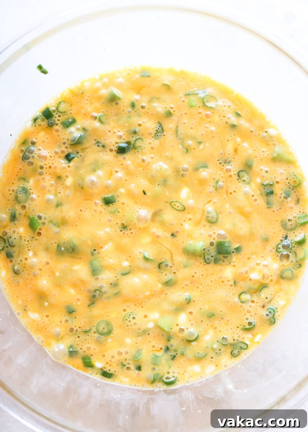 Hearty Protein Egg and Cottage Cheese Bake 5 All the wet ingredients for the Egg and Cottage Cheese Breakfast Bake, including eggs, cottage cheese, and green onions, mixed in a clear glass bowl.