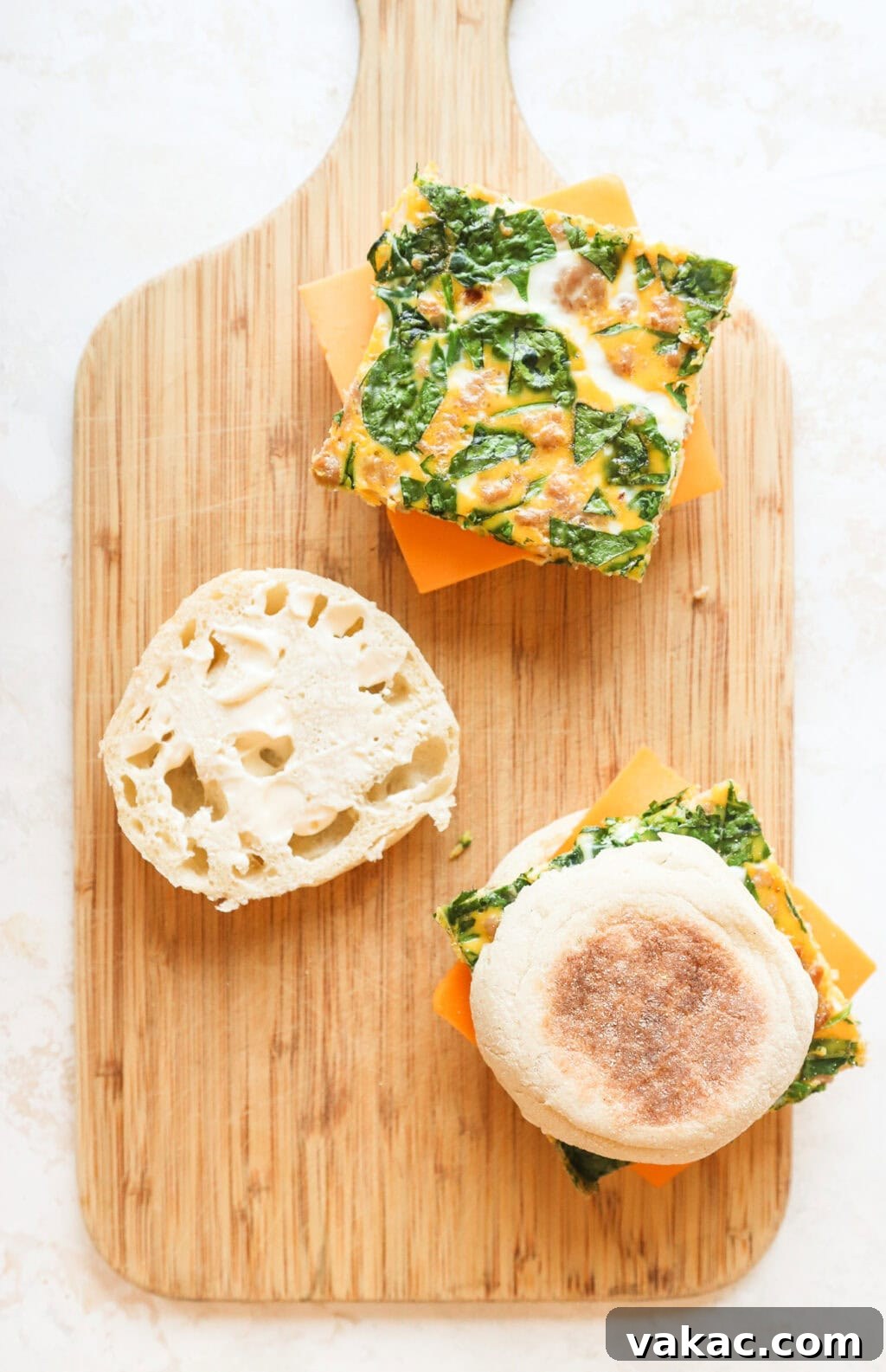 Effortless Turkey Sausage Breakfast Sandwiches 7 Overhead view of two assembled breakfast sandwiches on a cutting board, one open to show the layers.