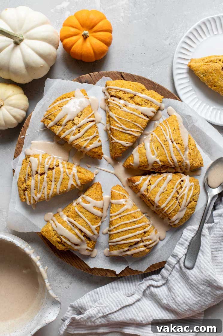 Spiced Pumpkin Delights 2 Delicious pumpkin scones arranged in a welcoming circle on parchment paper, each generously topped with a rich maple cinnamon glaze.