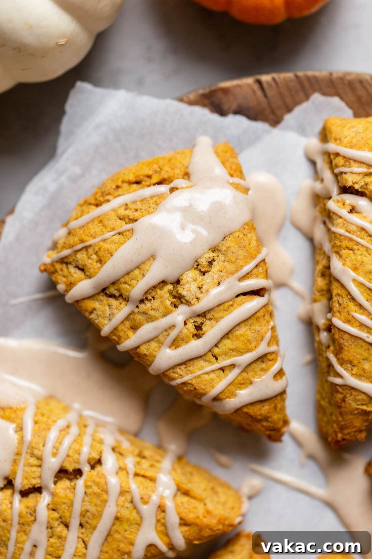 Spiced Pumpkin Delights 6 An inviting overhead shot of a freshly baked pumpkin scone, adorned with a delicate drizzle of maple cinnamon glaze, resting on a rustic wooden surface.