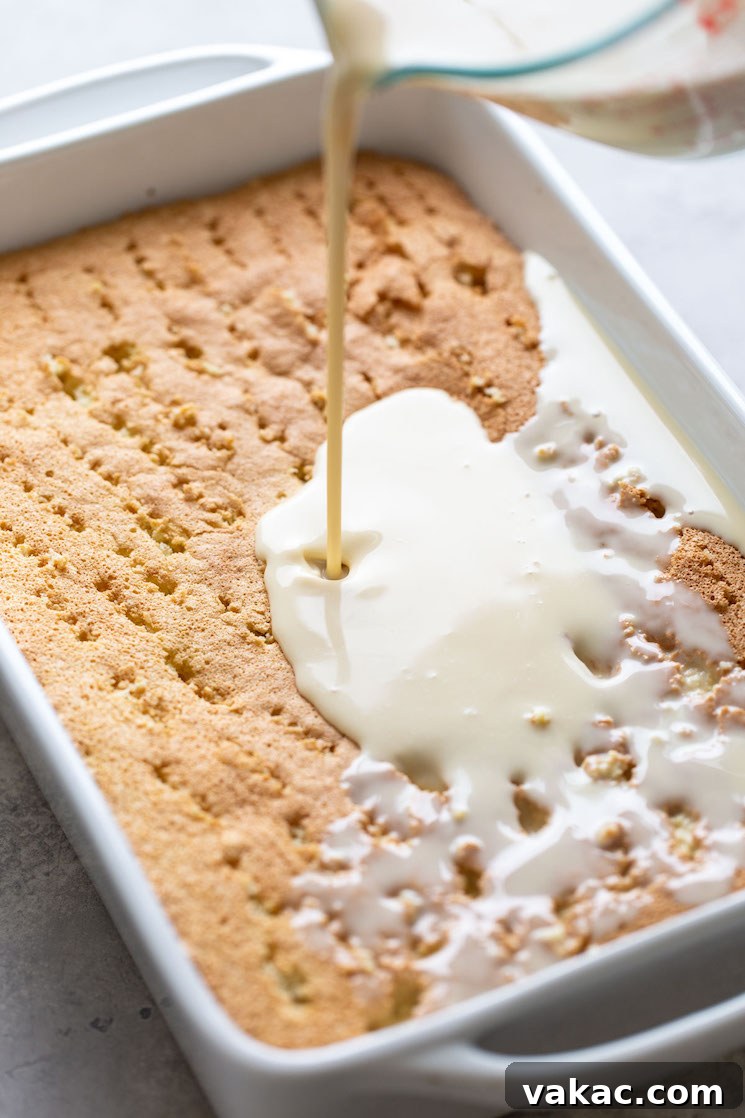A rich three-milk filling is slowly poured over a tender sponge cake that has been generously poked with holes, ensuring maximum absorption for a truly moist tres leches.