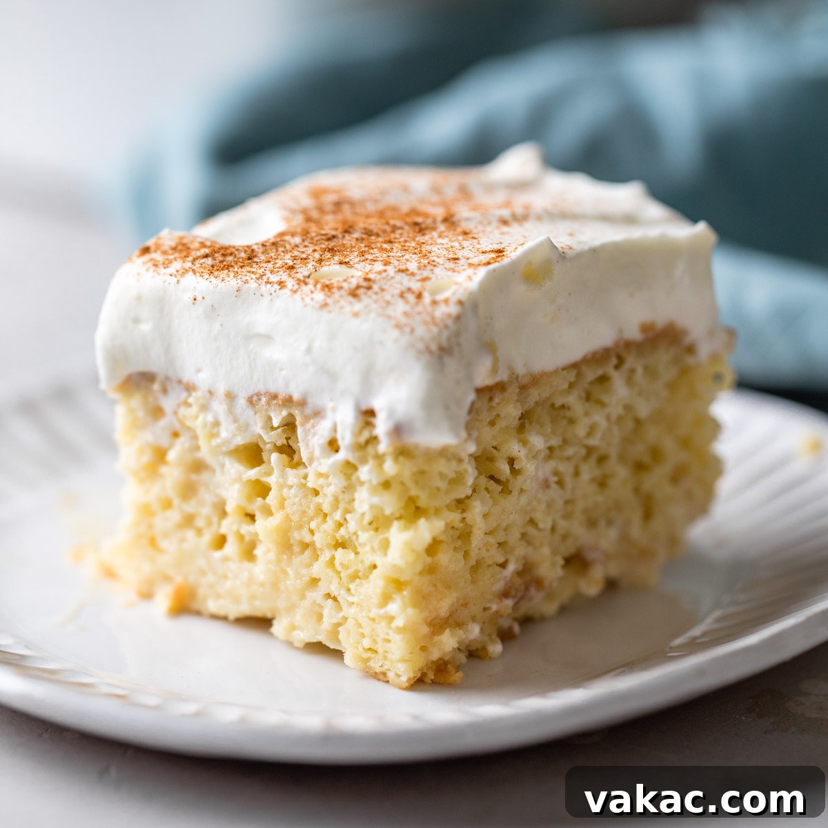 A tempting slice of tres leches cake sits on a clean white plate, ready to be enjoyed.