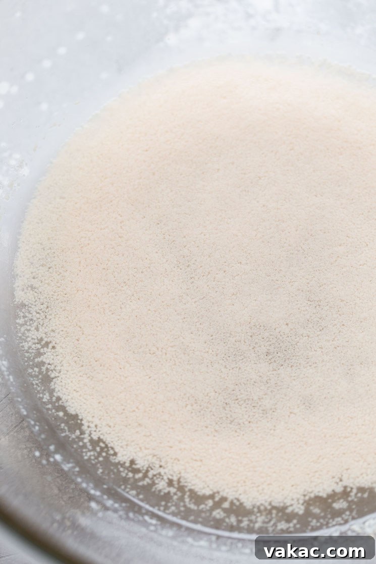 Bakery-Style Soft Pretzels 4 A glass mixing bowl with warm water, granulated sugar, and active dry yeast, proofing to a foamy mixture.