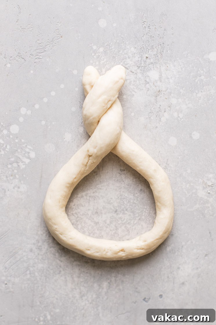 A roll of raw pretzel dough meticulously twisted and pressed into the iconic pretzel shape.