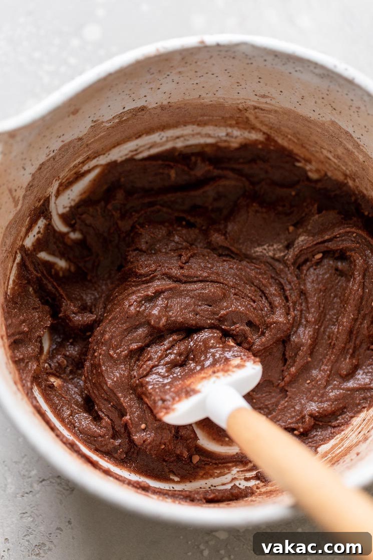 Microwaveable Mug Brownie Bliss 4 Overhead view of a mixing bowl filled with brownie batter. A rubber spatula is also in the bowl.