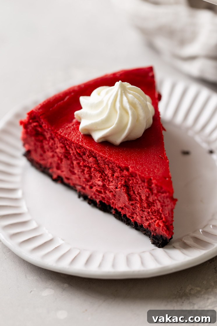 Crimson Dream Cheesecake 8 A slice of red velvet Oreo cheesecake on a white dessert plate.