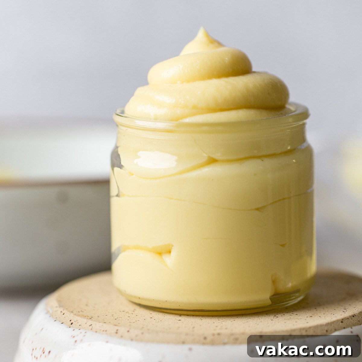 A straight on image of pastry cream in a glass jar. The jar is sitting on top of an overturned bowl.