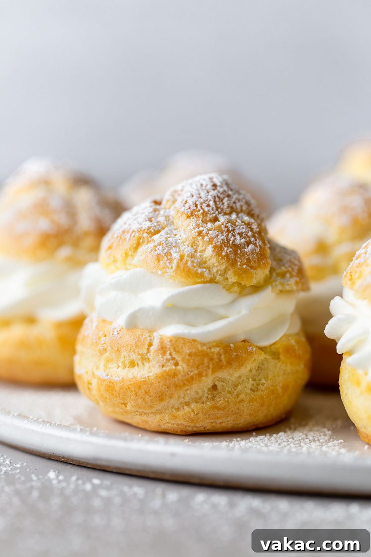 Sweet Cream Clouds 2 Side view of homemade cream puffs filled with whipped cream on a white plate.