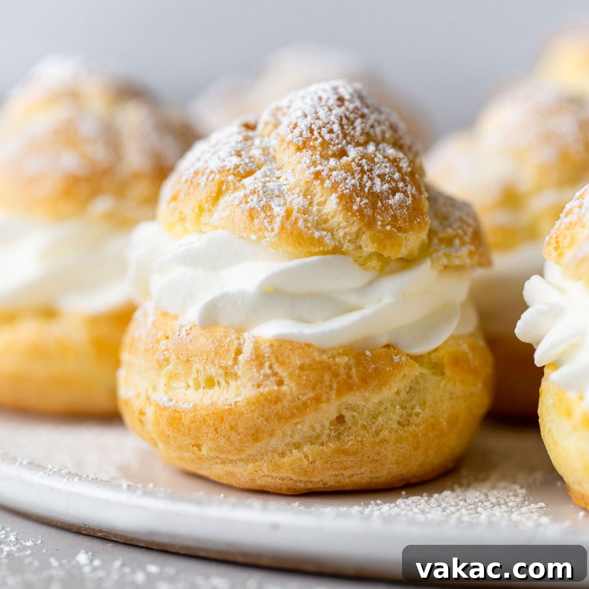 Sweet Cream Clouds 11 Side view of homemade cream puffs filled with whipped cream on a white plate.