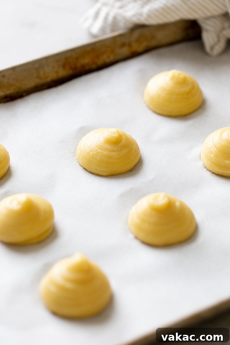 Sweet Cream Clouds 6 Choux pastry dough piped onto a parchment paper-lined baking tray.