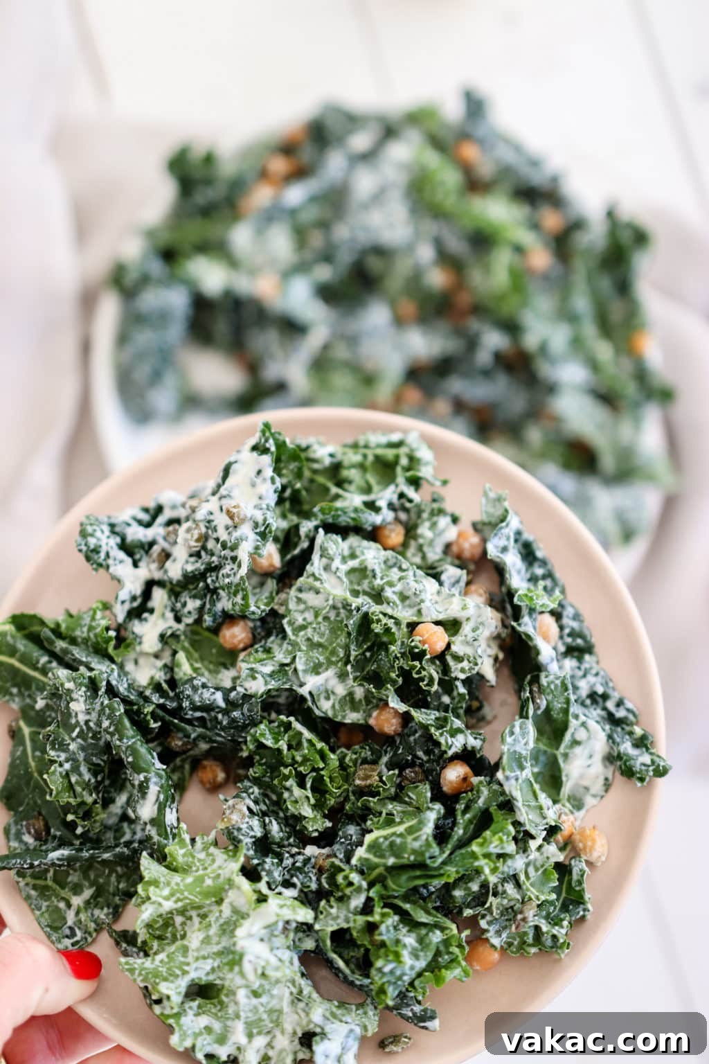 Lindsay Pleskot, RD holding chickpea kale caesar salad on a pink plate. Ingredients include: kale, chickpeas, capers, Greek yogurt, and garlic.