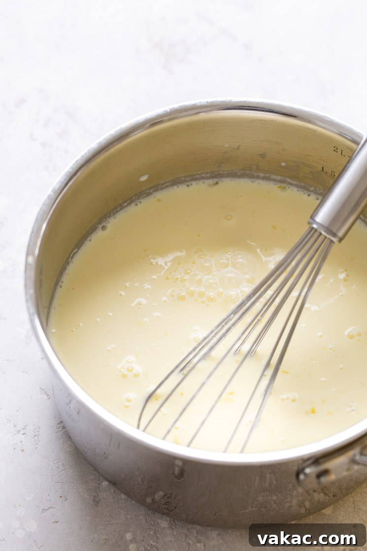 A saucepan filled with vanilla pudding. A whisk rests in the saucepan.