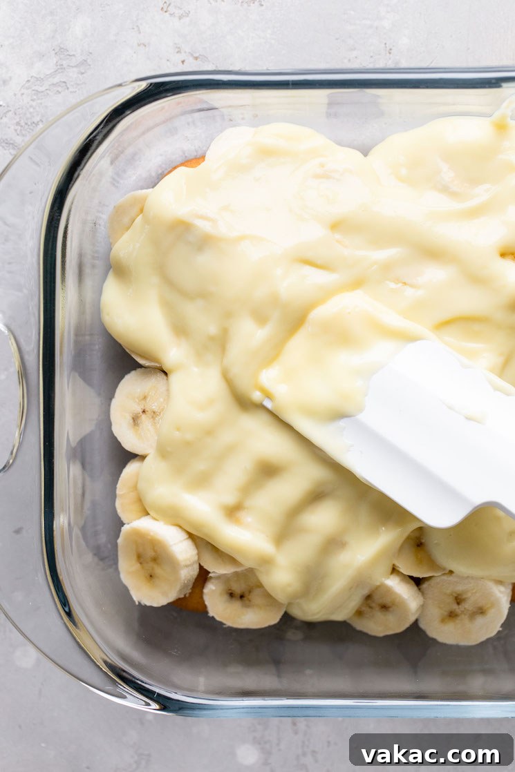 Southern Banana Dream 6 Overhead view of homemade vanilla pudding being spread over a layer of Nilla Wafers and banana slices.