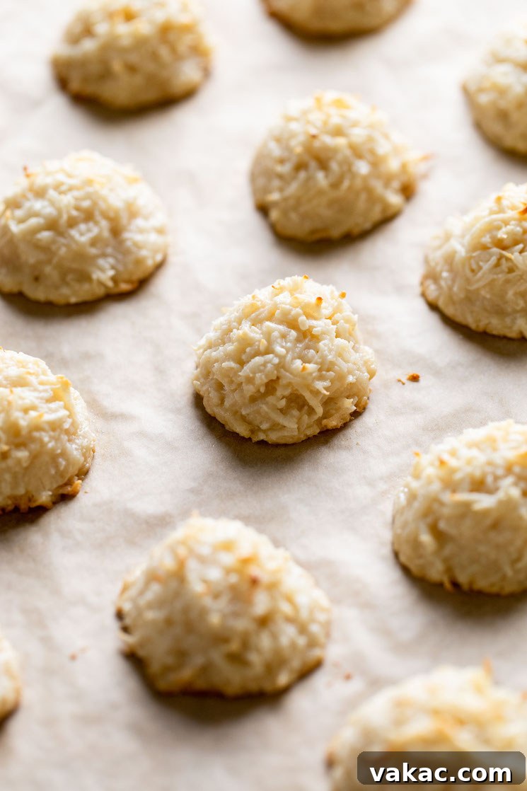 Baked coconut macaroons on a parchment paper-lined baking sheet.