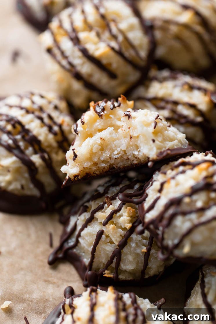 Chewy Toasted Coconut Macaroons 10 Close up view of a pile of chocolate dipped macaroon cookies. The top cookie has a bite missing.