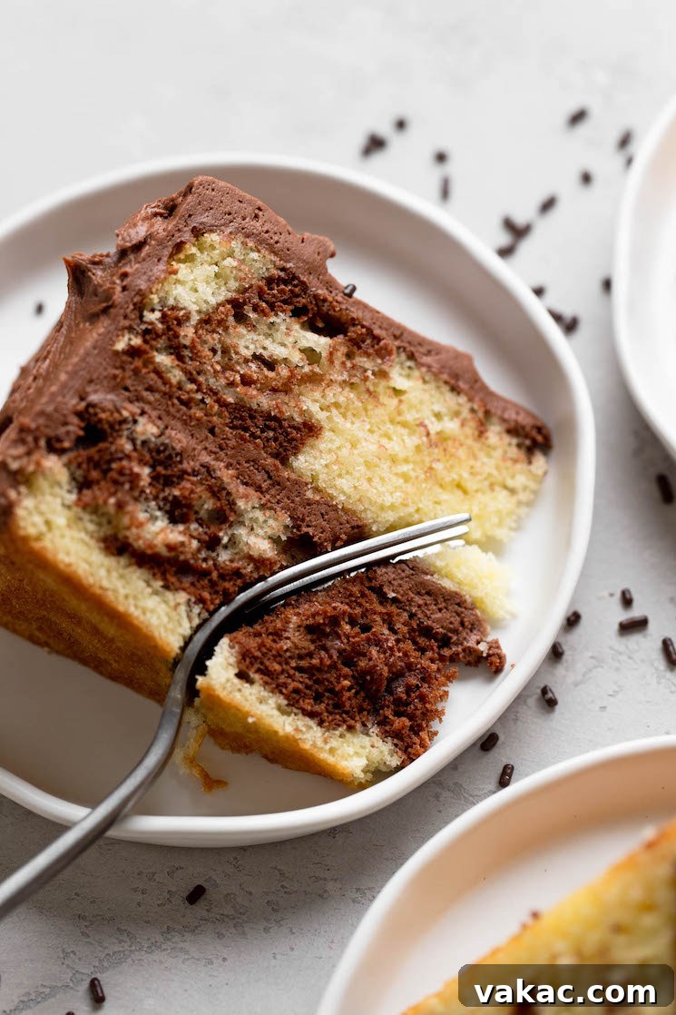 Marbled Perfection 9 An overhead view of a slice of marble cake on a white plate. A fork is digging into the slice.