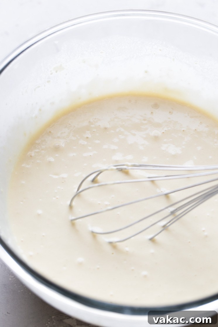 Perfect Fluffy Waffles 4 Waffle batter in a glass mixing bowl. A whisk rests in the mixing bowl.