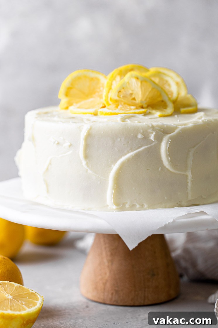 Sunshine Lemon Delight 2 A side view of a lemon layer cake garnished with lemon slices on a white cake stand.