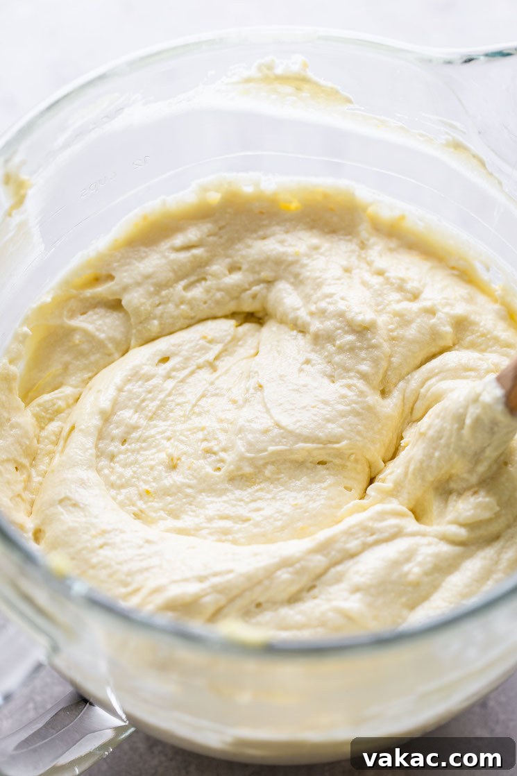 Sunshine Lemon Delight 5 Homemade lemon cake batter in a glass mixing bowl. A wooden spoon rests in the bowl.