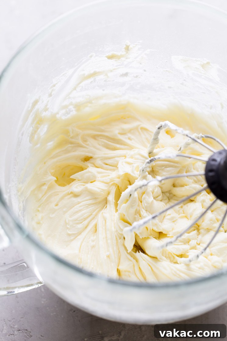 Sunshine Lemon Delight 6 A glass mixing bowl filled with lemon cake frosting. A whisk attachment rests in the bowl.
