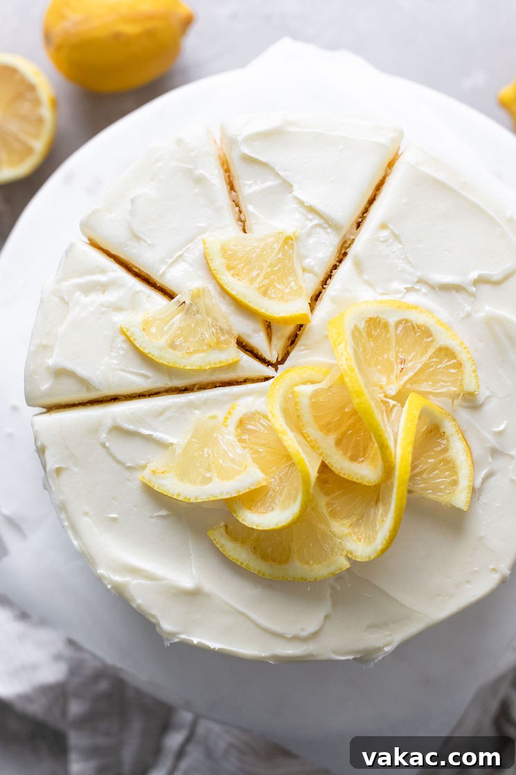 Sunshine Lemon Delight 7 An overhead view of a lemon layer cake on a cake stand. Three slices have been cut but not yet removed from the cake.