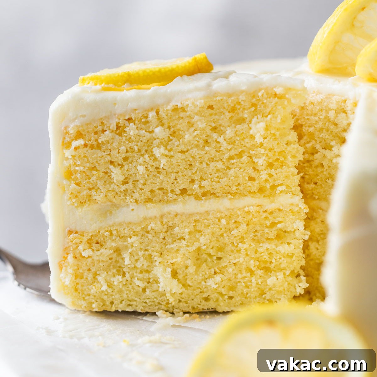 Sunshine Lemon Delight 10 A side view of a slice of lemon cake being removed from a cake stand.