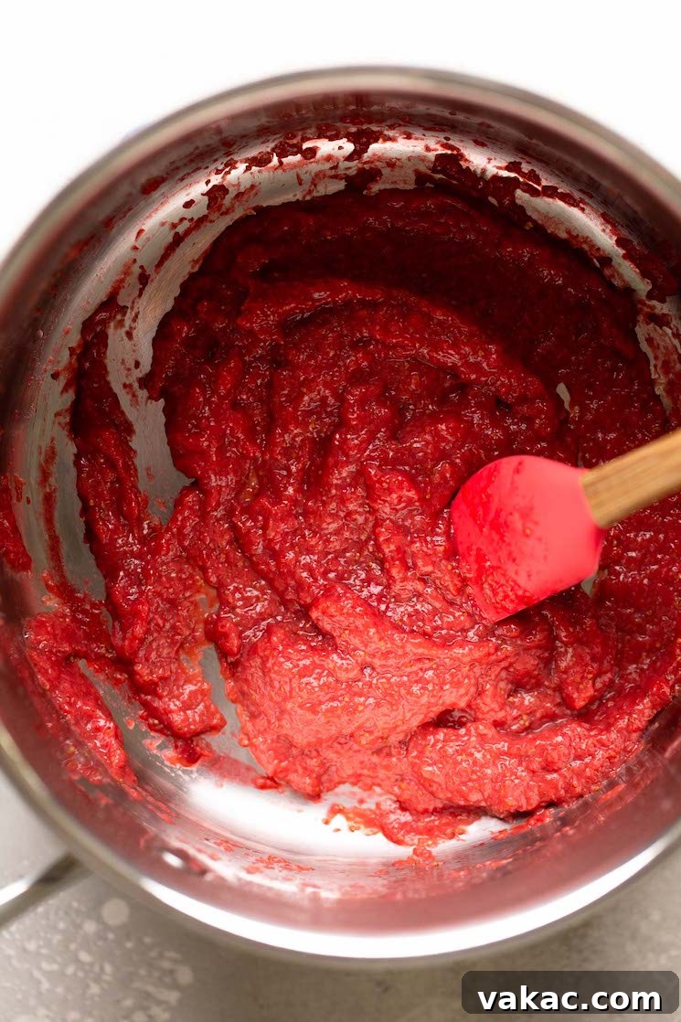 Luscious Strawberry Cupcakes 4 An overhead view of reduced strawberry puree in a saucepan. A rubber spatula rests in the pan.