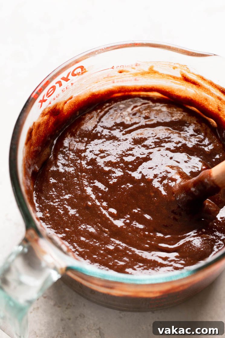 An overhead view of brownie batter in a glass bowl with a spoon.