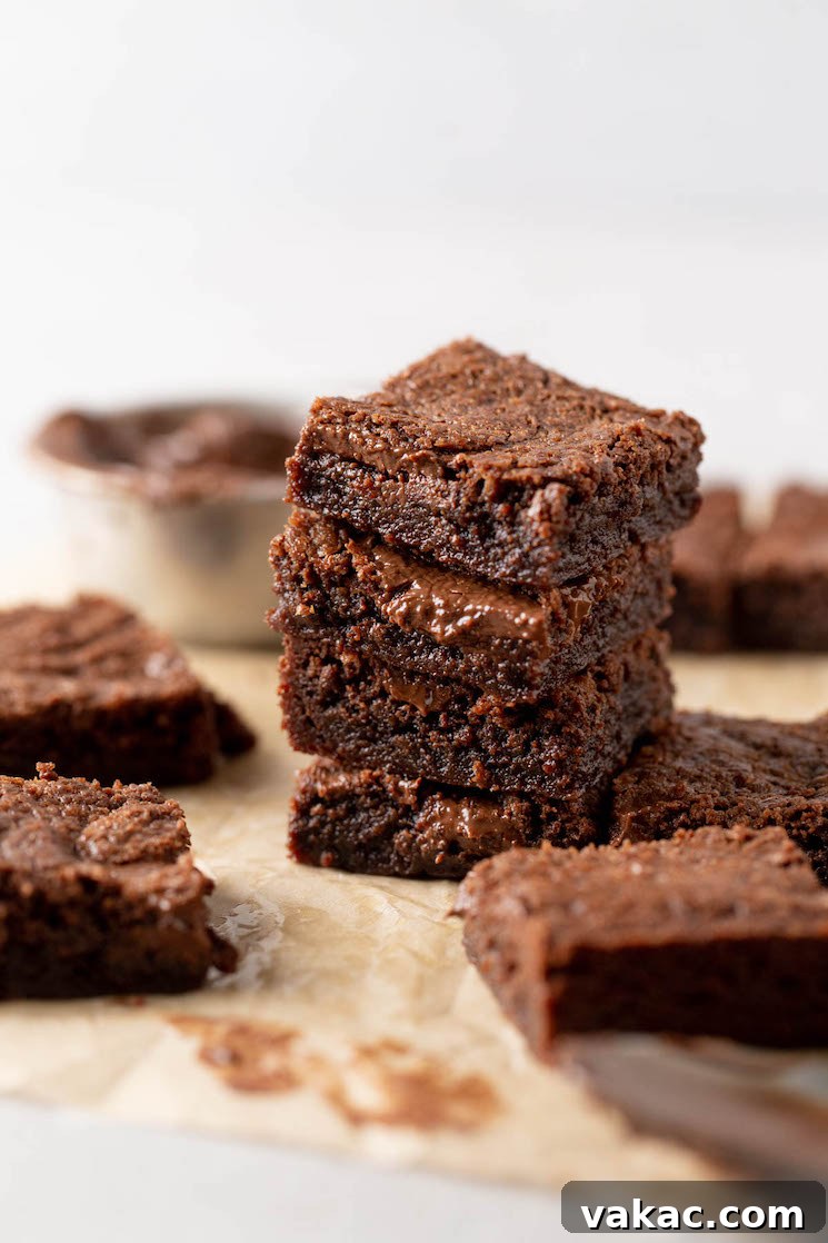 A stack of four brownies, with additional brownies scattered around. 