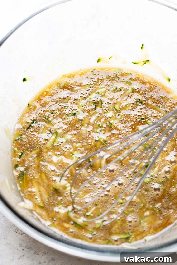 An overhead view of the wet ingredients for zucchini bread muffins in a mixing bowl.