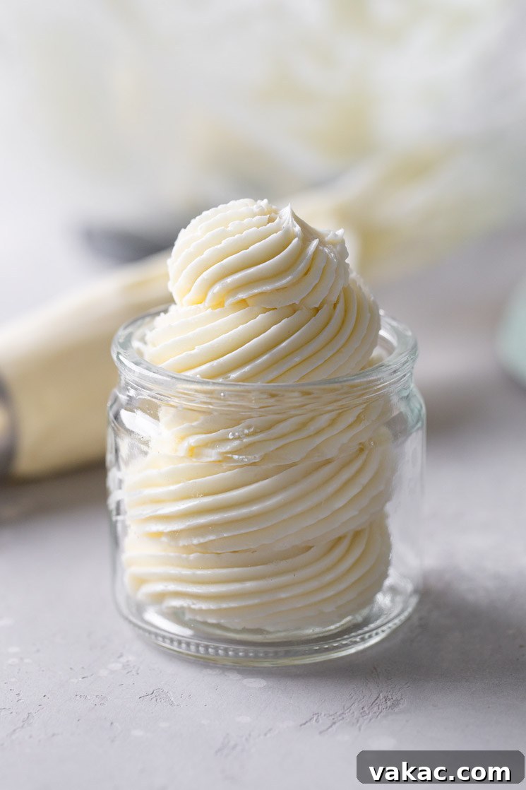Velvet Meringue Frosting 2 Swiss meringue buttercream frosting piped into a glass jar. A piping bag lies in the background.