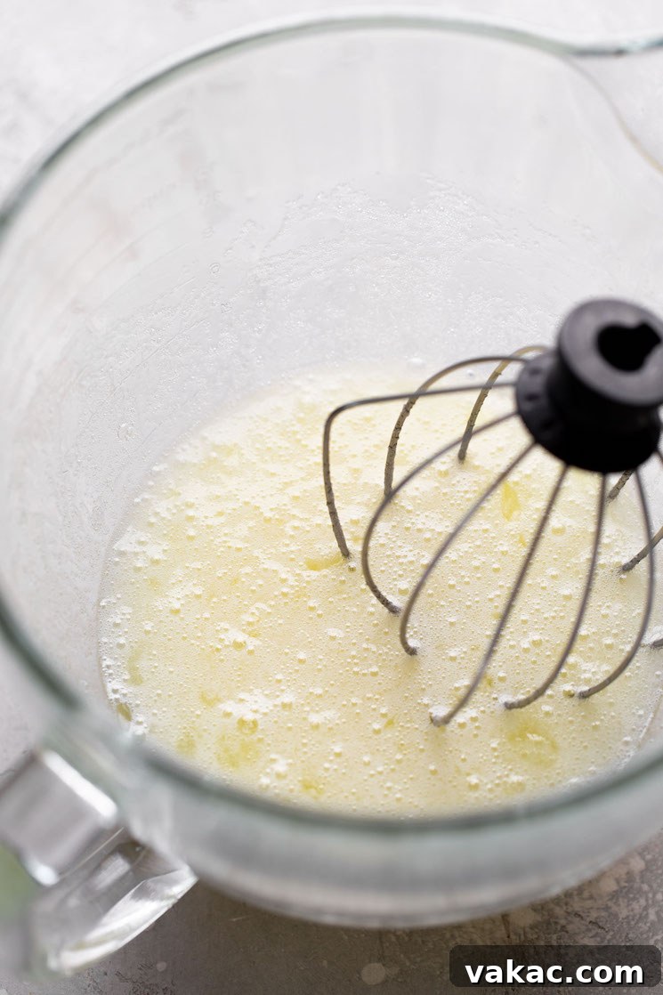 Velvet Meringue Frosting 4 An overhead view of egg whites in a glass mixing bowl with a whisk.