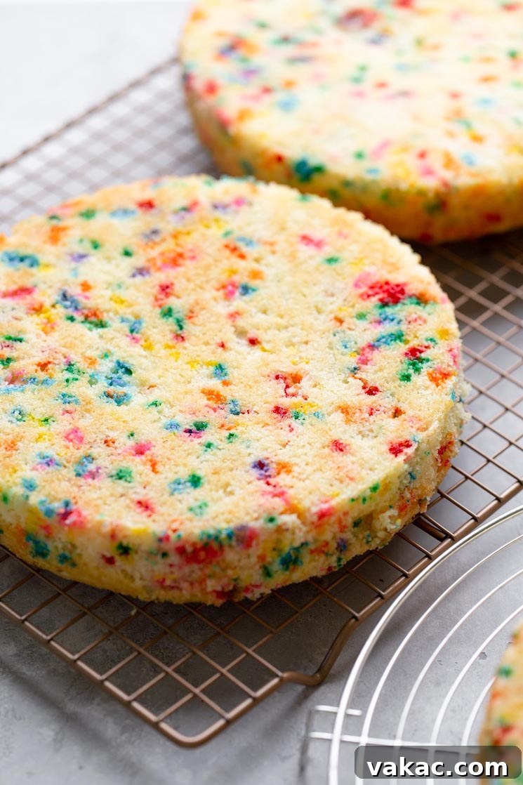 Funfetti birthday cake layers cooling on a wire rack.