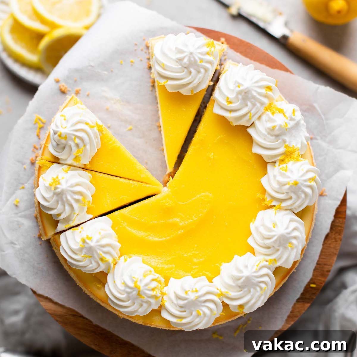 Tangy Lemon Cloud 8 An overhead view of a lemon cheesecake topped with lemon curd and whipped cream. The cheesecake has been partially sliced and one slice has been removed.