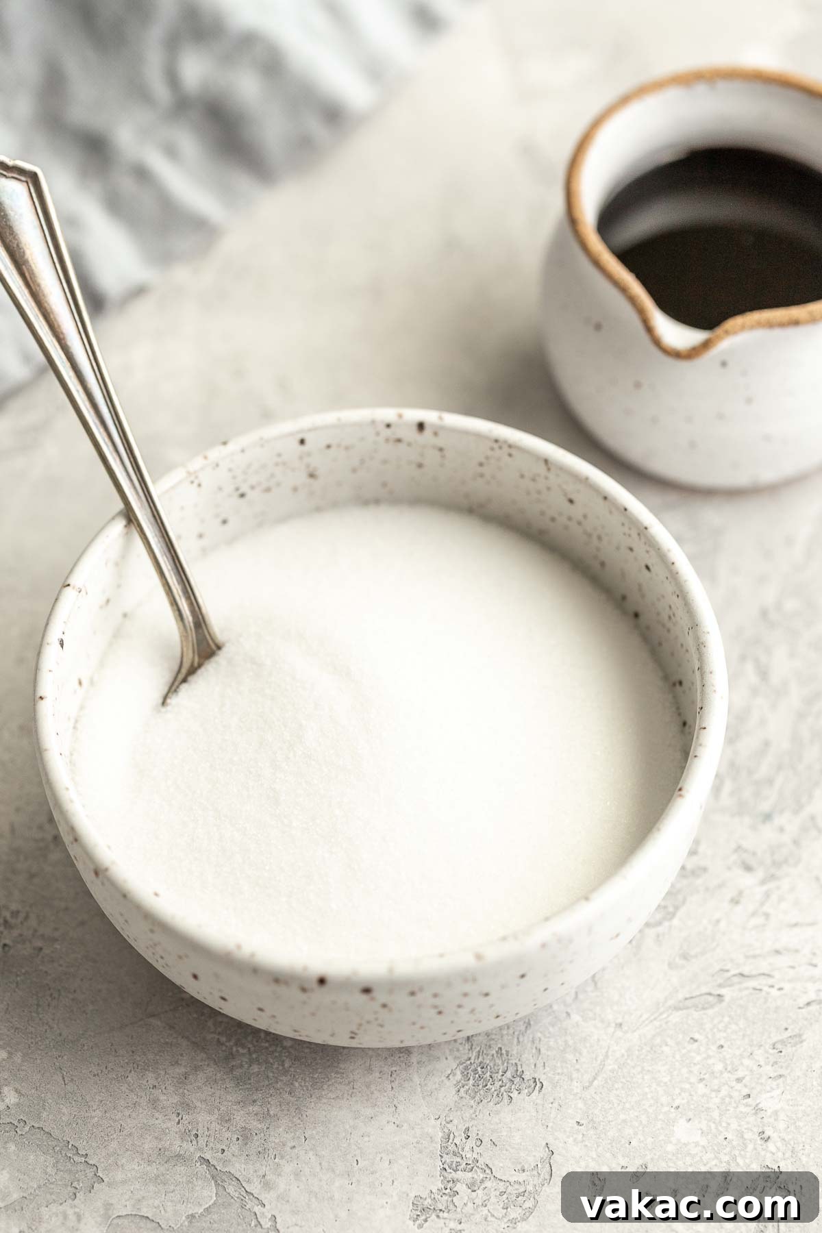 A bowl of white granulated sugar placed next to a small jug of molasses, ready for mixing.