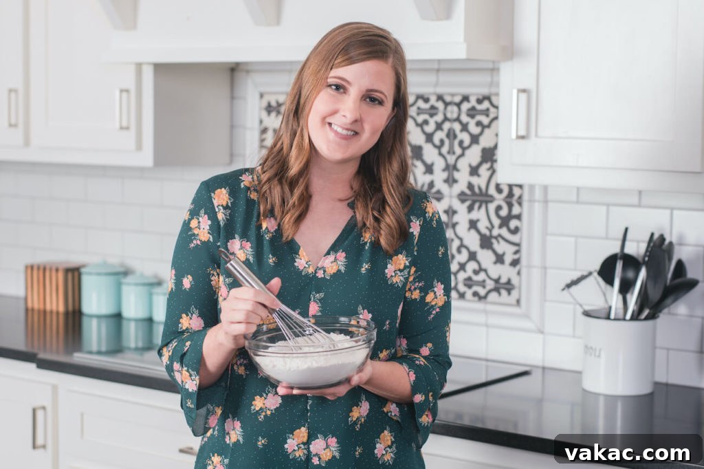 Recipes and Real Life 2 A picture of Danielle in a green shirt holding a mixing bowl with dry ingredients and a whisk, smiling warmly.